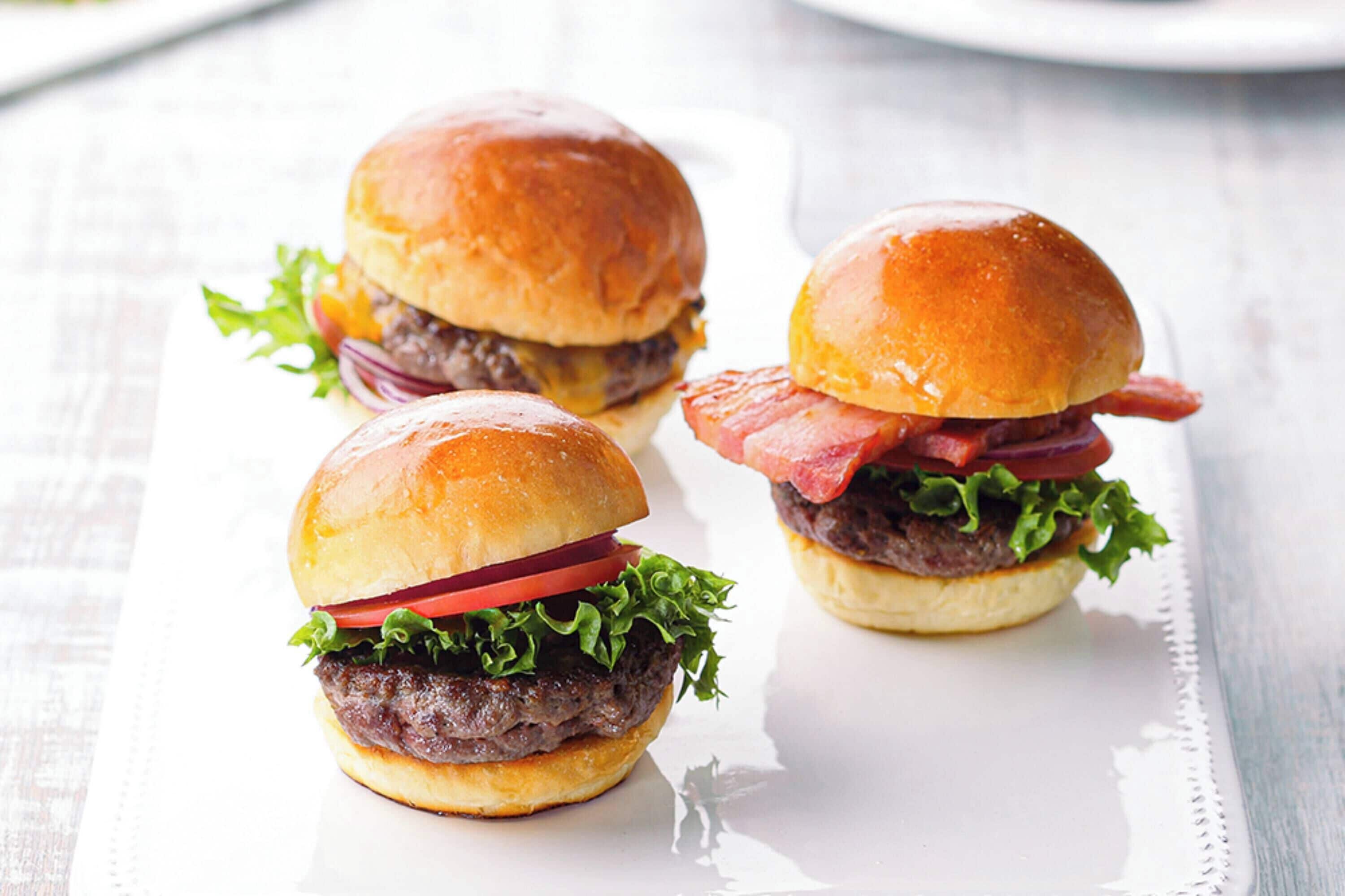Three burgers on a white plate.