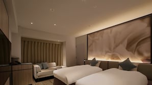 Une chambre d’hôtel avec deux lits, un canapé, un bureau et une grande œuvre d’art abstraite accrochée au mur.