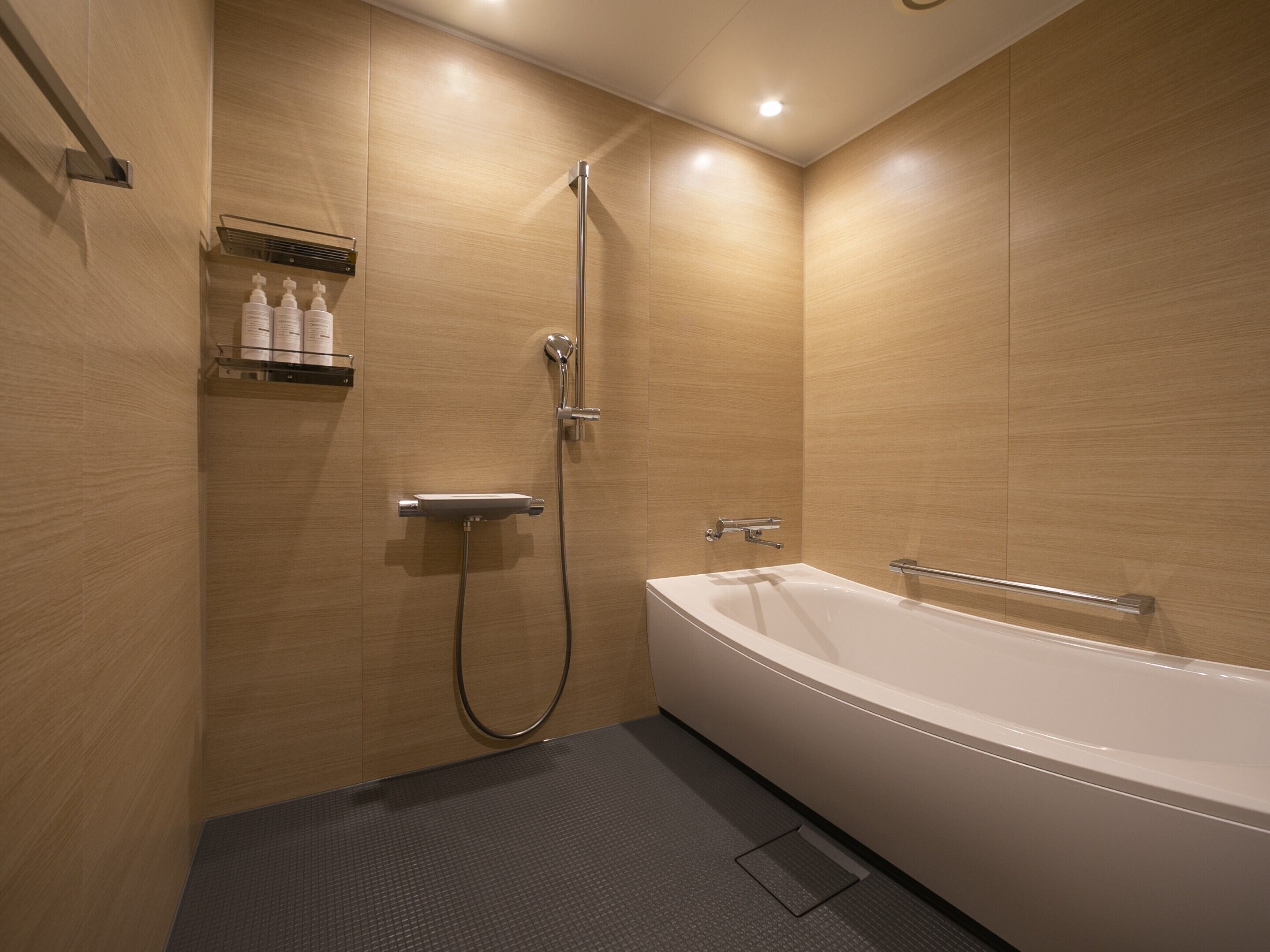 A modern bathroom with a bathtub, shower, and a shelf with toiletries.