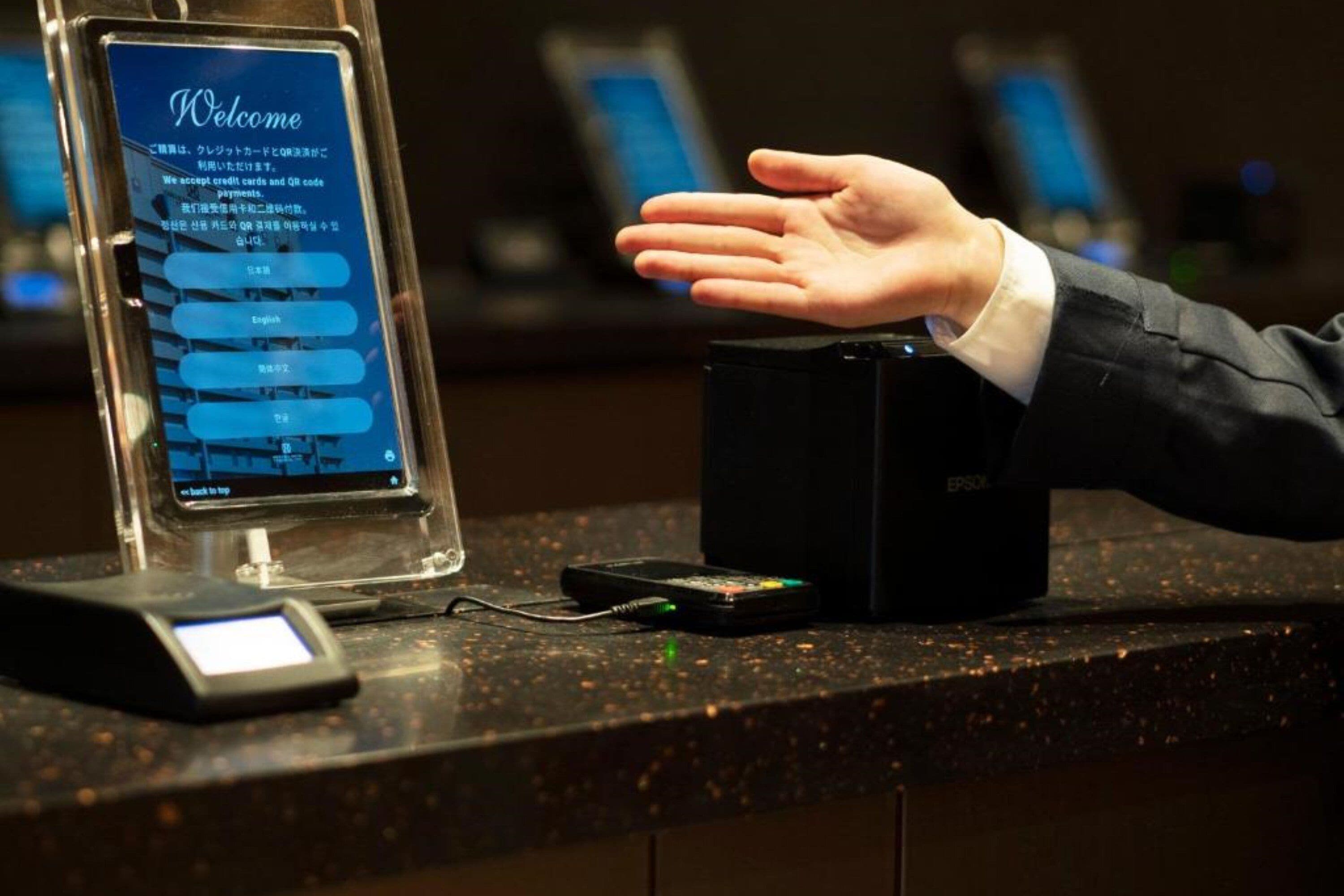 A reception desk with a digital screen displaying a welcome message and language selection options.