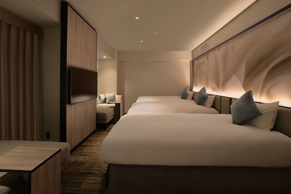 A modern hotel room with a large bed, a desk, and a seating area.