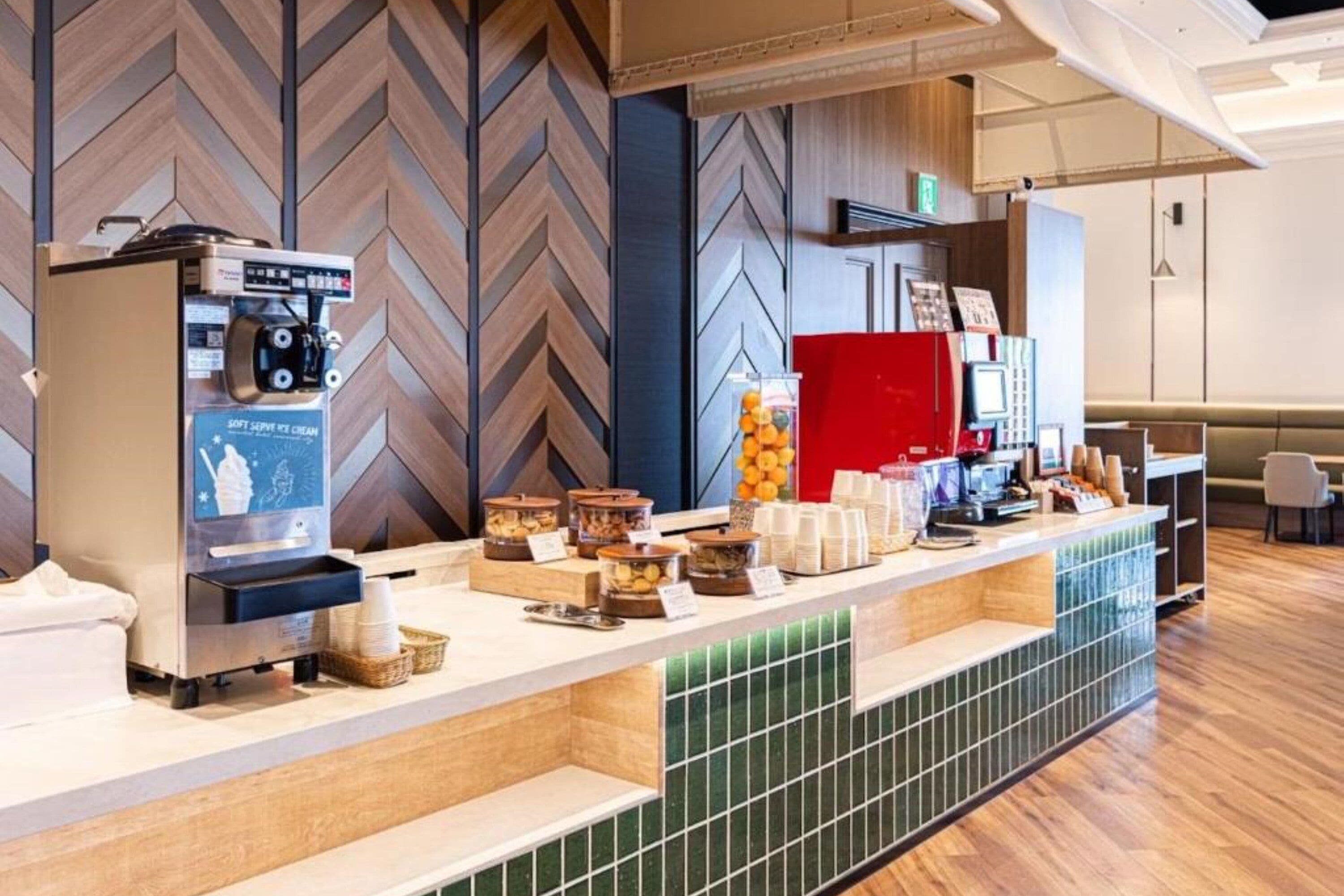 A hotel reception area with a coffee machine, self-serve ice cream, and a variety of food containers.