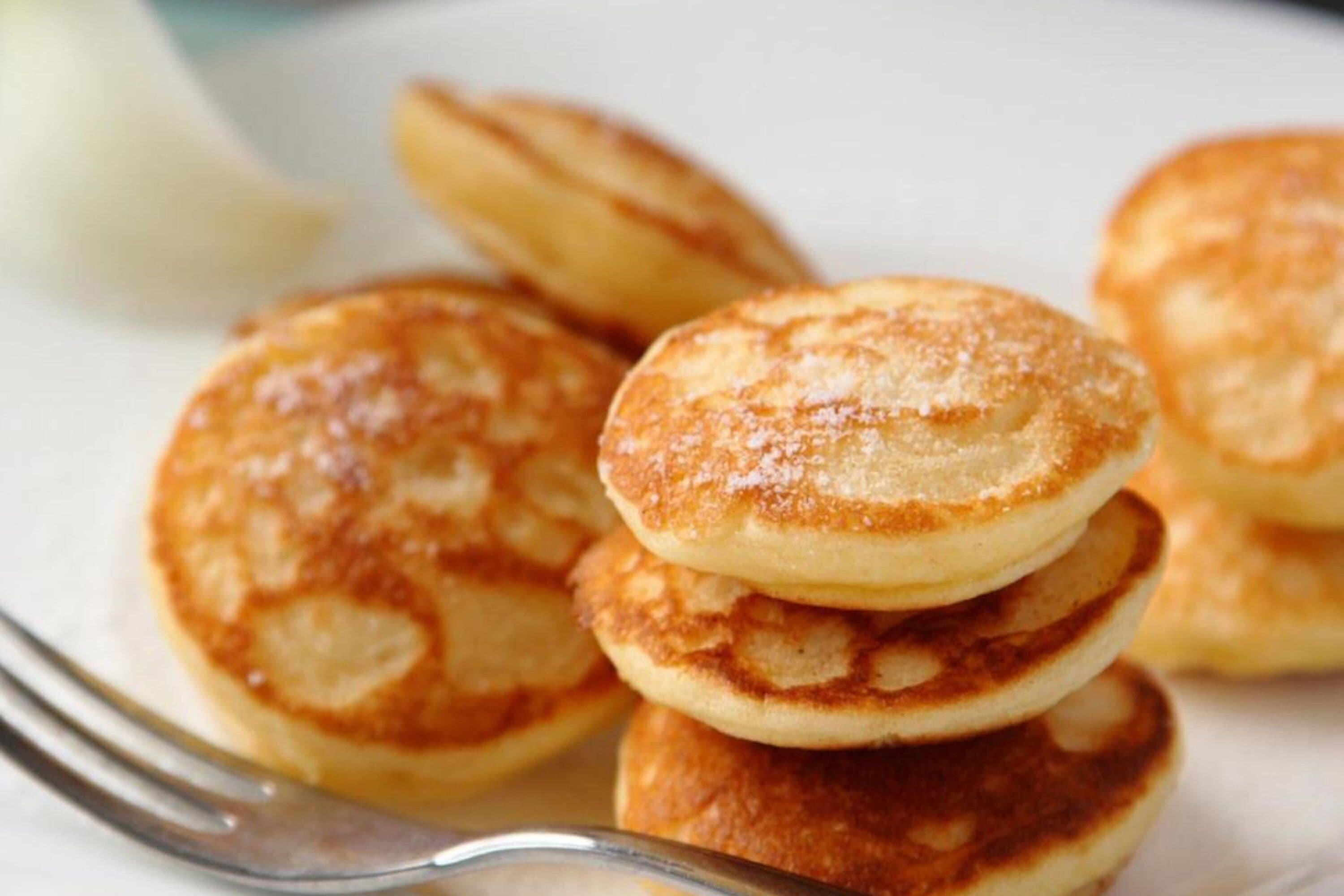 A stack of golden-brown pancakes with a dusting of powdered sugar.