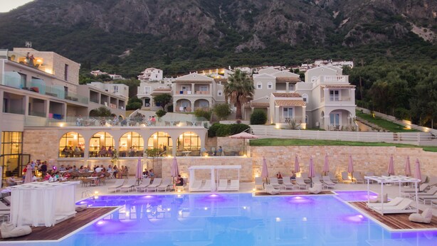 A resort with a swimming pool, outdoor seating, and a view of the surrounding mountains. - Golden Mare - All Inclusive (Corfu)