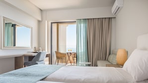 Una habitación de hotel con cama, escritorio, silla y balcón con vistas.