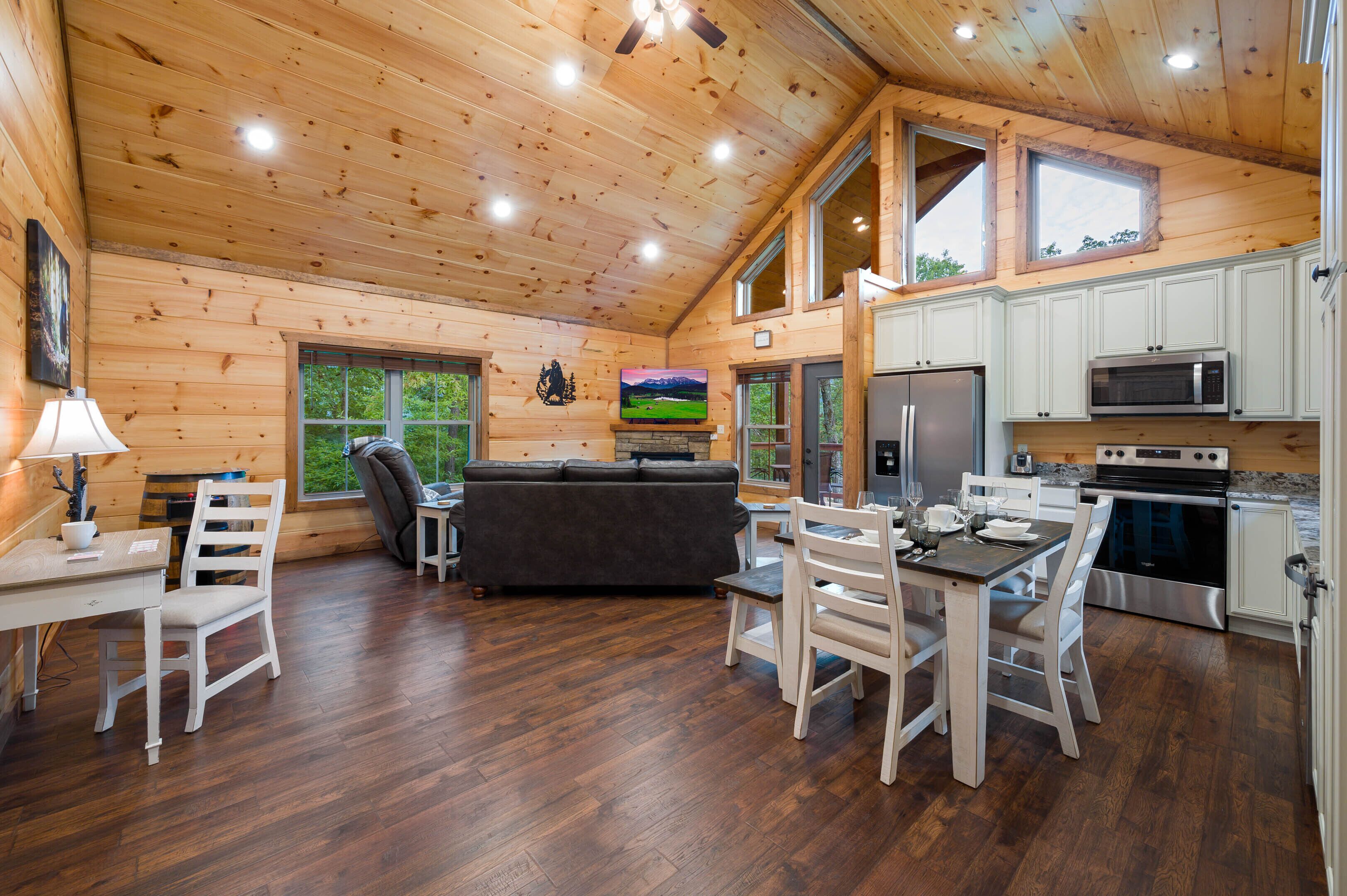 A wooden cabin interior with a dining area, kitchen, and living space.