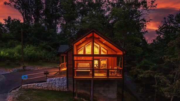 A wooden cabin with a balcony, surrounded by trees.