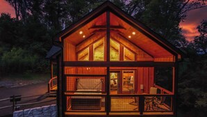 A wooden cabin with a balcony, a bed, and a small kitchen area.