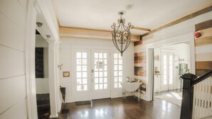 A spacious hallway with wooden floors, white doors, and a chandelier. - Beautiful, Restored Historic Craftsman House, Perfect for groups! (Birmingham)