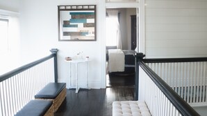 A spacious hallway with a high ceiling, a ceiling fan, a hanging light fixture, a bench, a small table, and a framed artwork on the wall. - Beautiful, Restored Historic Craftsman House, Perfect for groups! (Birmingham)