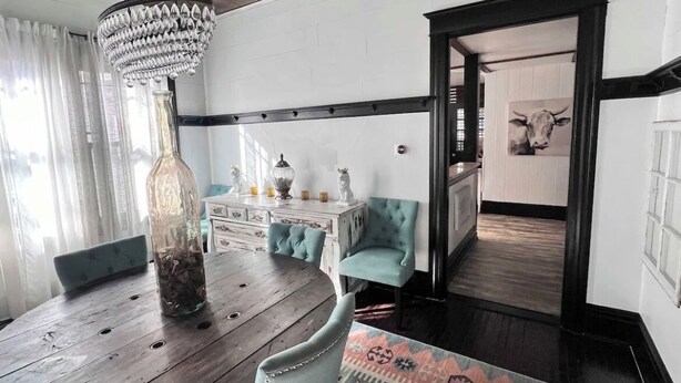 A dining area with a wooden table, chairs, a chandelier, and a patterned rug. - Beautiful, Restored Historic Craftsman House, Perfect for groups! (Birmingham)