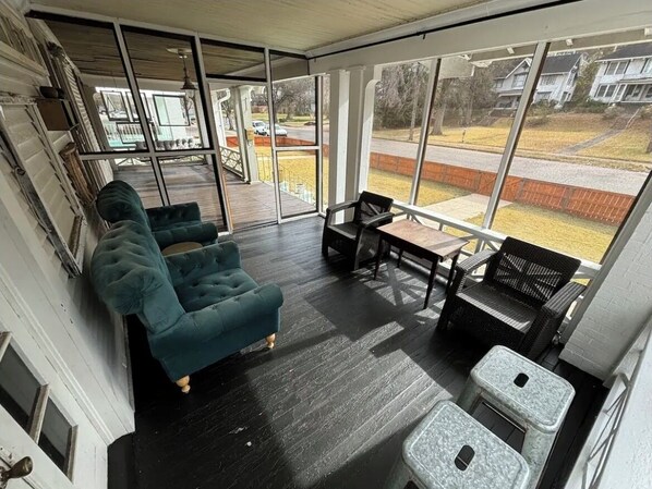 A sunroom with a large glass door, a wooden deck, and a seating area with a table and chairs. - Beautiful, Restored Historic Craftsman House, Perfect for groups! (Birmingham)