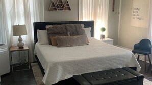 A bedroom with a bed, a ceiling fan, a nightstand, a lamp, a chair, and a rug. - Beautiful, Restored Historic Craftsman House, Perfect for groups! (Birmingham)