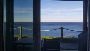 Blick aus einem Gebäude auf das Meer, mit einem Seil und einer Bank.