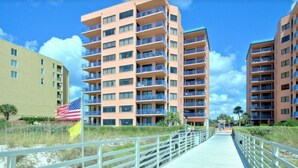 A multi-story hotel with balconies, a boardwalk, and an American flag.