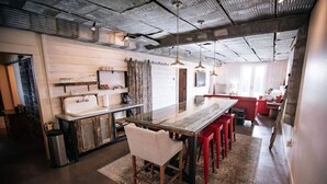 Et moderne køkken med en central ø, røde barstole og et rustikt loft.