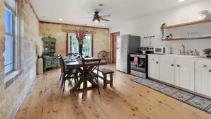 A rustic kitchen with wooden flooring, a dining table, and a built-in refrigerator.