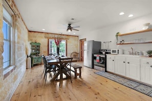 A rustic kitchen with wooden flooring, a dining table, and a built-in refrigerator.