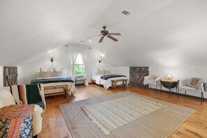 A spacious attic bedroom with a sloped ceiling, two beds, a large rug, and a ceiling fan. - Luxury w/Fire Pit-Amazing Views (Fredericksburg)