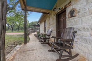 A rustic stone building with a covered porch and rocking chairs.