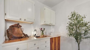 A kitchen with white cabinets, a wooden countertop, and a potted plant.
