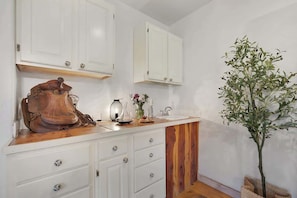 A kitchen with white cabinets, a wooden countertop, and a potted plant.