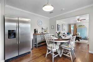 Una cocina moderna con un refrigerador de acero inoxidable, una mesa de comedor de madera y sillas blancas.