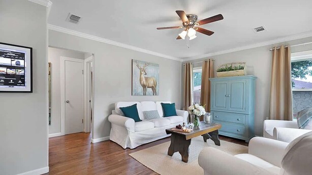 A living room with a white sofa, a wooden coffee table, a ceiling fan, and a blue cabinet. - Charming Home |4 Blks from Main (Fredericksburg)