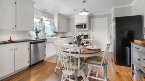 A modern kitchen with white cabinetry, a dining table with chairs, and a black refrigerator. - Charming Home |4 Blks from Main (Fredericksburg)