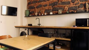 Une cuisine avec un mur en pierre, un téléviseur à écran plat, un évier et un réfrigérateur Samsung.