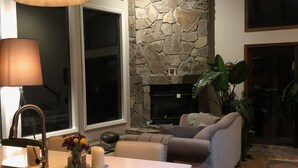 A modern kitchen with a stone accent wall, a ceiling fan, and a dining area with a sofa and a rug. - Magical River Wonderland (Burnsville)