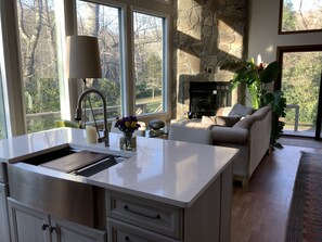 Een moderne keuken met een groot eiland, een stenen openhaard en uitzicht op de omgeving.