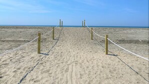 A sandy beach with a rope barrier leading to the water. - DOG FRIENDLY - Second Row ...Ruff Life beach cottage. (Oak Island)