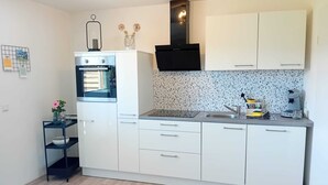 Een moderne keuken met witte kasten, een ingebouwde oven, een zwarte afzuigkap en een spatbescherming met spikkels.