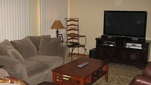 A living room with a sofa, a wooden coffee table, a TV, and a lamp. - Camping in paradise @ a bargain (Cape Coral)