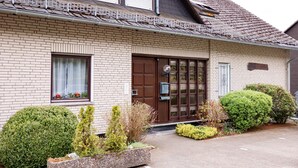 A two-story brick building with a brown door and window shutters, surrounded by well-maintained landscaping. - Ferienwohnung mit Seeblick Sport und Erholung (Winterberg)
