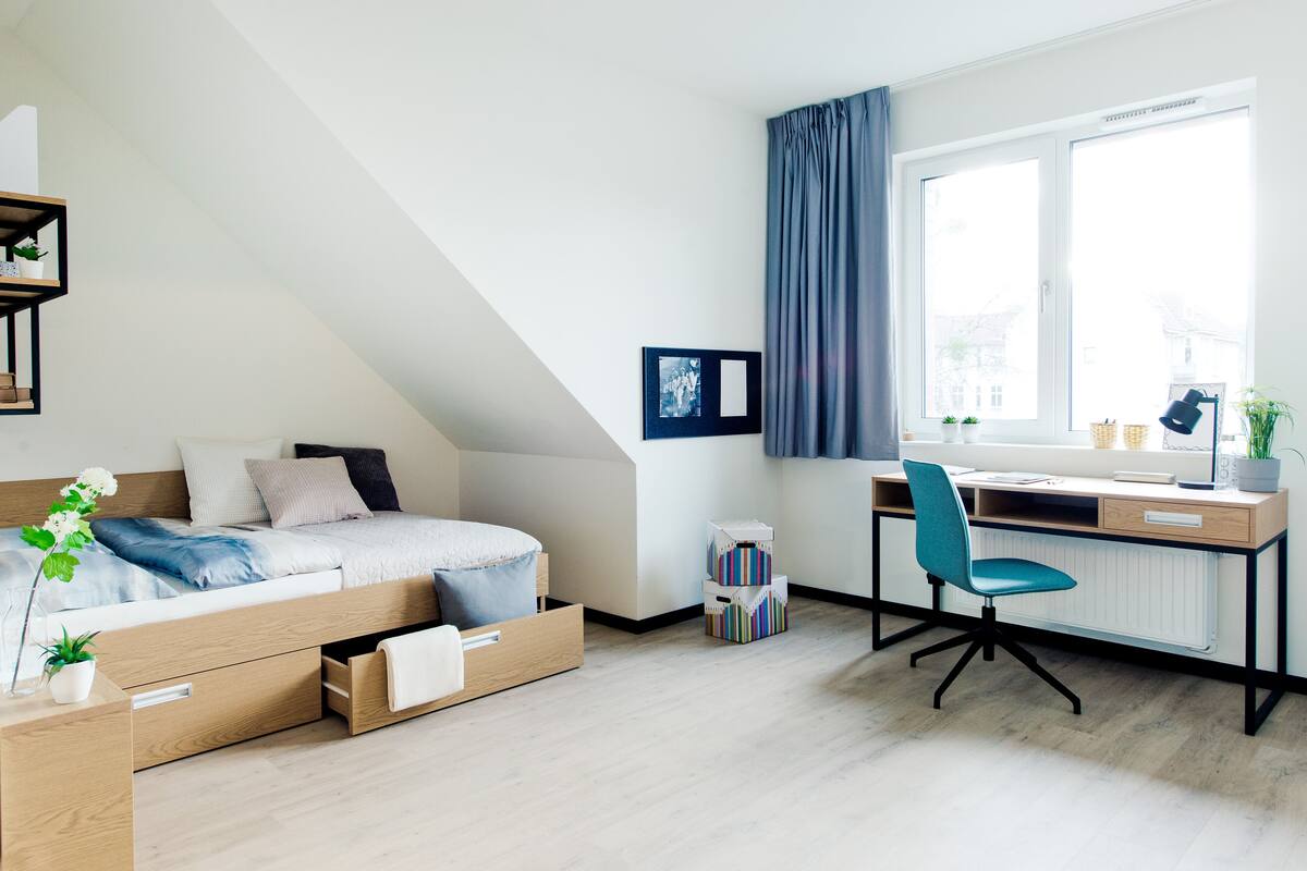 Een moderne slaapkamer met een hoogslaper, bureau en raam met gordijnen.