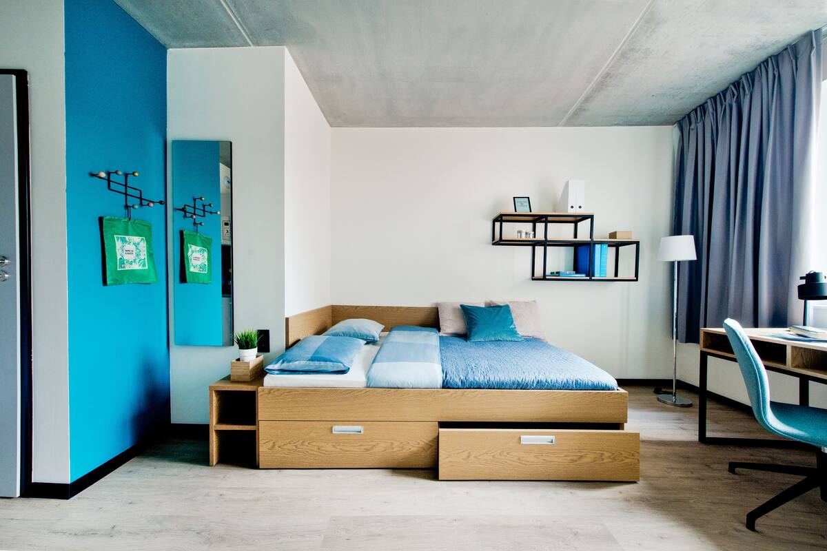 Een moderne slaapkamer met een bed, een bureau en een stoel.