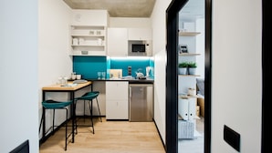 A compact kitchen with white cabinets, a teal backsplash, and a stainless steel refrigerator. - YOUNIQ Gdansk - Campus Accommodation (Gdansk)