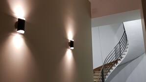 A modern staircase with a metal railing and a light fixture on the wall.