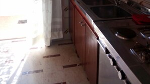Uma cozinha com armários de madeira, pia de aço inoxidável e fogão a gás.