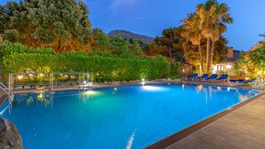 A swimming pool with lounge chairs and a view of trees and a mountain.