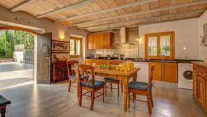 A spacious kitchen with wooden cabinets, a dining table with chairs, and a washing machine. - Llobiman, Villa-Finca 5StarsHome Mallorca (Pollensa / Pollença)