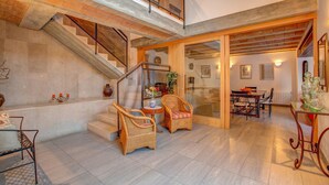 A spacious interior with a staircase leading to an upper level, wicker furniture, and a dining area. - Llobiman, Villa-Finca 5StarsHome Mallorca (Pollensa / Pollença)