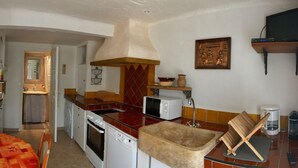 Un espacio habitable compacto con sofá, una mesa de comedor, una cocina con estufa, microondas y lavabo, y una pequeña zona de estar.