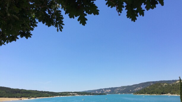 Un paisaje costero con playa arenosa, aguas azules tranquilas y barcos.