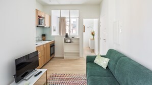 A modern apartment with a kitchen, a living area with a green sofa, and a TV. - Le Moulin des Carmélites 1 - Appt moderne à Rennes (Rennes)