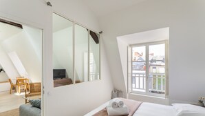 Een slaapkamer met een bed, raam, stoel en televisie.