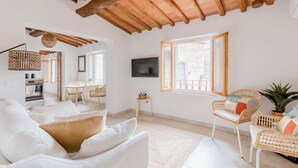 Ein geräumiges Wohnzimmer mit hohen Decken, einem Essbereich und einer Küche.
