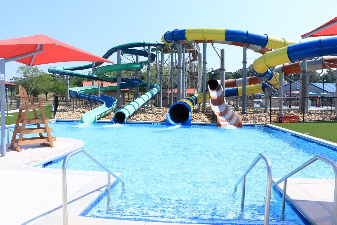 Una piscina con varias toboganes y una silla de madera.